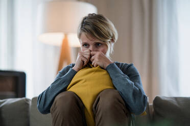 Worried woman with tablet indoors on sofa at home feeling stressed, mental health concept. - HPIF14032