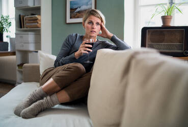 Depressed and lonely woman with wine indoors at home, mental health and alcohol addiction concept. - HPIF14033