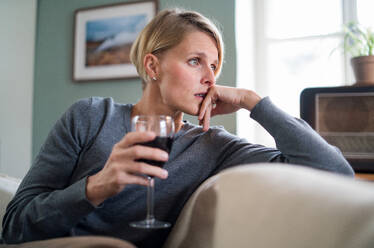 Depressive und einsame Frau mit Wein zu Hause, psychische Gesundheit und Alkoholabhängigkeit Konzept. - HPIF14034