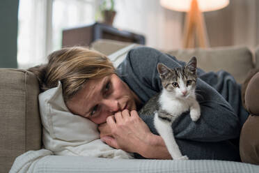 Frau mit Katze drinnen auf Sofa zu Hause gestresst, psychische Gesundheit Konzept. - HPIF14037