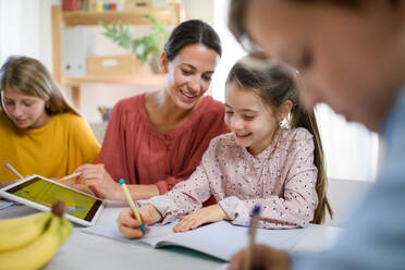 Eine Gruppe von Kindern, die zu Hause unterrichtet werden, mit einem Lehrer, der drinnen lernt, Konzept des Coronavirus. - HPIF14042