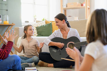 Group of cheerful homeschooling children with teacher having music lesson indoors, coronavirus concept. - HPIF14062