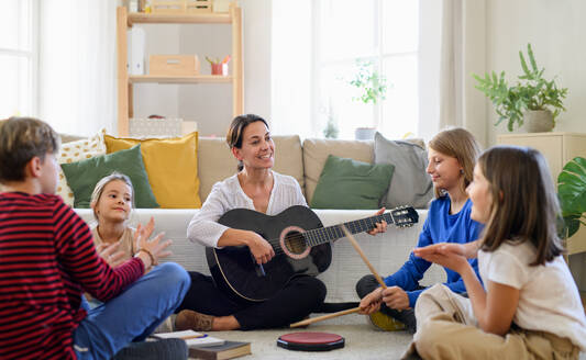 Eine Gruppe fröhlicher Heimschüler mit einer Lehrerin, die drinnen Musikunterricht hat, Konzept des Coronavirus. - HPIF14063