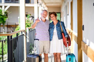 Älteres Ehepaar mit Gepäck vor der Wohnung im Urlaub, zurück zum normalen Konzept. - HPIF14075