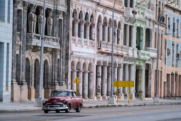 Faded grandeur, stucco, weather-beaten houses on seafront of Malecon, with red classic car, Havana, Cuba, West Indies, Caribbean, Central America - RHPLF24064