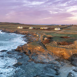 Aerial view of Constantine Bay at sunset highlighting the clifftop cottages, Cornwall, United Kingdom. - AAEF17918