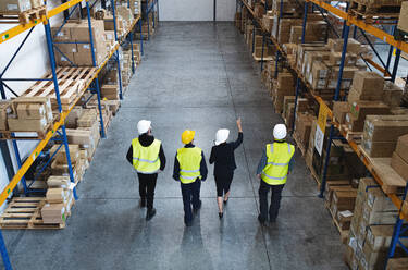 Top rear view of a group of workers with manager working indoors in warehouse, coronavirus concept. - HPIF14102