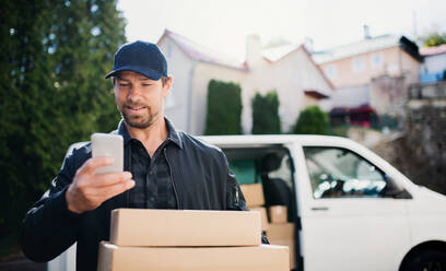 Ein Kurier liefert mit seinem Smartphone ein Paket in der Stadt aus. - HPIF14110