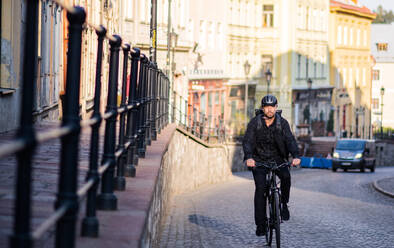 Front view of delivery man courier with bicycle cycling in small town. - HPIF14118