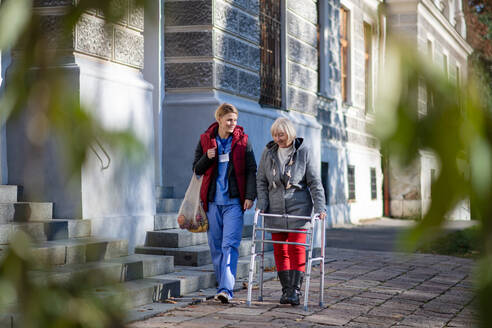 Glückliche Seniorin mit Rollator und Betreuerin im Freien in der Stadt, Einkaufen und Coronavirus-Konzept. - HPIF14136