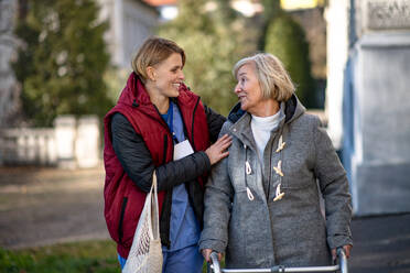 Glückliche Seniorin mit Rollator und Betreuerin im Freien in der Stadt, Einkaufen und Coronavirus-Konzept. - HPIF14138