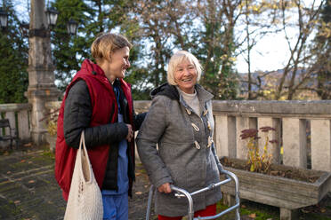 Glückliche Seniorin mit Rollator und Betreuerin im Freien in der Stadt, Einkaufen und Coronavirus-Konzept. - HPIF14143