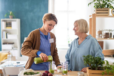 Ältere Frau mit Pflegerin oder medizinischem Personal im Haus, die einen gesunden Smoothie trinken. - HPIF14170