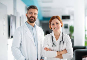Ein Porträt eines Mannes und einer Ärztin, die im Krankenhaus stehen und in die Kamera schauen. - HPIF14202