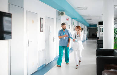 Porträt eines Mannes und einer Ärztin, die im Krankenhaus spazieren gehen und sich unterhalten; Raum kopieren. - HPIF14240