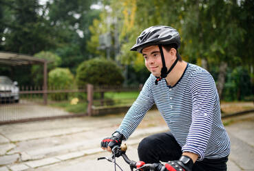 A portrait of down syndrome adult man with bicycle cycling outdoors on street. - HPIF14267