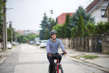 Ein Porträt von Down-Syndrom erwachsenen Mann mit Fahrrad Radfahren im Freien auf der Straße. - HPIF14268