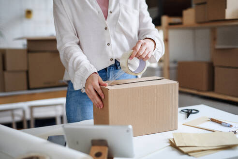 Mittelteil einer nicht erkennbaren Dropshipper-Frau, die zu Hause arbeitet und Pakete packt, Konzept des Coronavirus. - HPIF14302