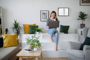 Young woman student with laptop and smartphone working at home, coronavirus concept. - HPIF14307