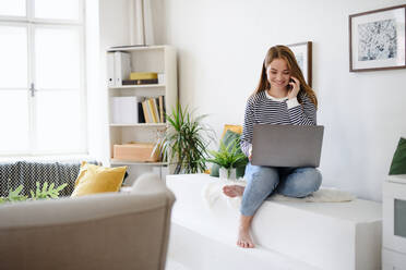 Young woman student with laptop and smartphone working at home, coronavirus concept. - HPIF14309