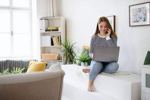 Junge Studentin mit Laptop und Smartphone bei der Arbeit zu Hause, Coronavirus-Konzept. - HPIF14309