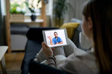 Ill young woman having video call with doctor on tablet at home, online consultation concept. - HPIF14326