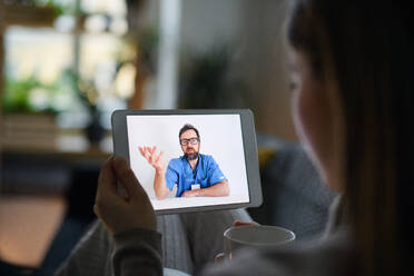 Eine kranke junge Frau führt ein Videogespräch mit einem Arzt auf einem Tablet zu Hause, Konzept der Online-Konsultation. - HPIF14327