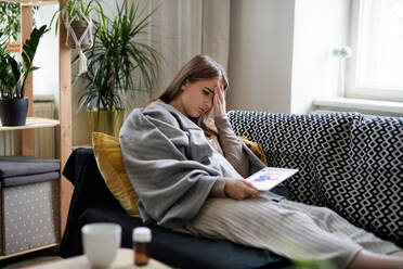 An ill young woman having video call with doctor on tablet at home, online consultation concept. - HPIF14331