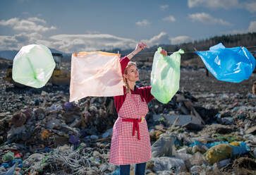 Woman housewife on landfill, consumerism versus plastic pollution concept. - HPIF14350