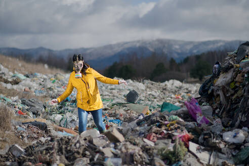 Frau mit Gasmaske, die auf einer Mülldeponie spazieren geht, Umweltkonzept, Raum kopieren. - HPIF14373