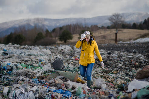 Frau mit Gasmaske, die auf einer Mülldeponie spazieren geht, Umweltkonzept, Raum kopieren. - HPIF14375