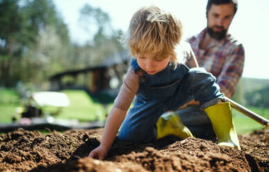 Mature father with small son working outdoors in garden, sustainable lifestyle concept. - HPIF14487