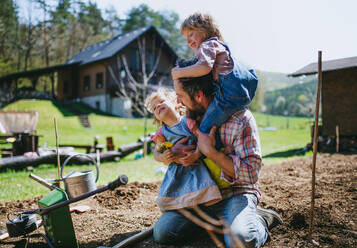 Älterer Vater mit kleinen Kindern bei der Arbeit im Garten, Konzept des nachhaltigen Lebensstils. - HPIF14490