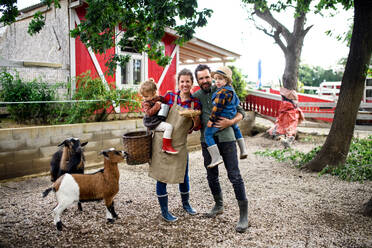 Porträt einer glücklichen Familie mit kleinen Kindern auf einem Bauernhof, die einen Korb mit Eiern halten. - HPIF14503