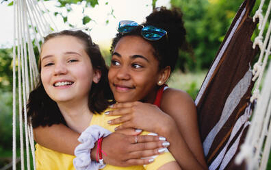 Front view of cheerful young teenager girls friends outdoors in garden, resting. - HPIF14595