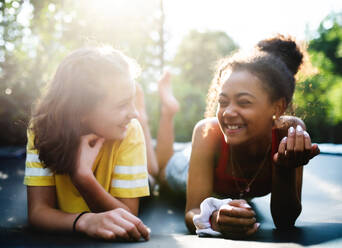 Frontansicht von fröhlichen jungen Teenager-Mädchen, die sich im Garten unterhalten und lachen. - HPIF14598