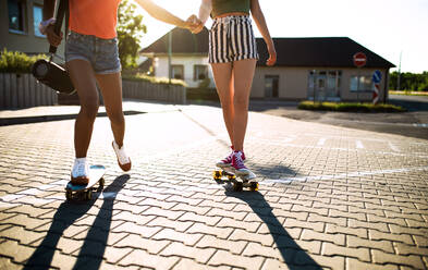 Nicht erkennbare Teenager-Freundinnen mit Skateboards und tragbaren Lautsprechern im Freien in der Stadt, Mitte. - HPIF14608