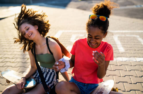 Teenager Mädchen Freunde mit Skateboards sitzen im Freien in der Stadt, Spaß haben. - HPIF14609