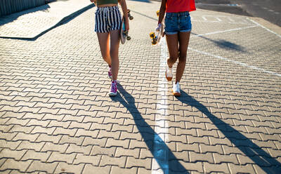 Unkenntlich Teenager-Mädchen Freunde mit Skateboards zu Fuß im Freien in der Stadt, midsection. - HPIF14647