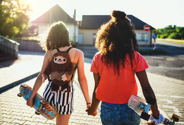 Rückansicht von Teenager-Mädchen Freunde mit Skateboards zu Fuß im Freien in der Stadt. - HPIF14648