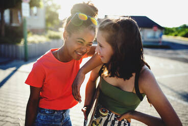 Teenager girls friends with skateboards standing outdoors in city, having fun. - HPIF14652