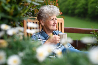 Porträt einer älteren Frau mit Kaffee auf der Terrasse im Sommer, die sich ausruht. - HPIF14707