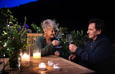 Glückliches älteres Paar trinkt abends auf der Terrasse Wein. - HPIF14725