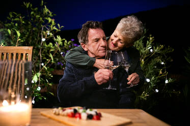 Porträt eines älteren Paares am Abend auf der Terrasse beim Weintrinken. - HPIF14729