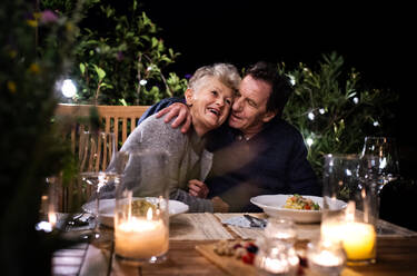 Porträt eines glücklichen älteren Paares beim abendlichen Essen auf der Terrasse. - HPIF14738