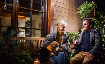 Porträt eines älteren Paares im Rollstuhl mit Hund am Abend auf der Terrasse, Wein trinkend. - HPIF14748
