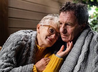 Nahaufnahme eines älteren Paares, das abends auf der Terrasse sitzt und sich umarmt. - HPIF14757