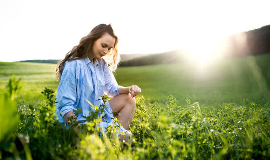 Porträt eines jungen Mädchens, das draußen in der Natur auf einer Wiese sitzt. - HPIF14852