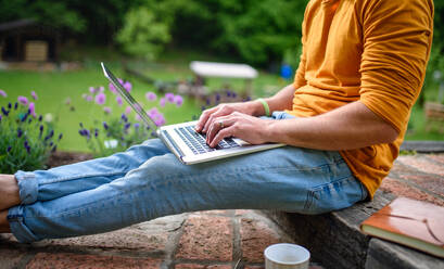 Midsection von unerkennbaren Mann mit Laptop arbeiten im Freien im Garten, Home-Office-Konzept. - HPIF14889