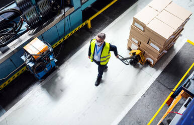 Aerial view of man worker or technician with protective mask working in industrial factory or warehouse. - HPIF15004